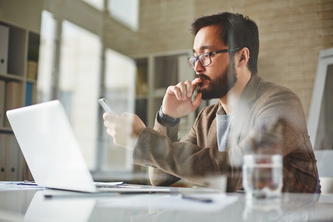 Thoughtful man with computer and smartphone