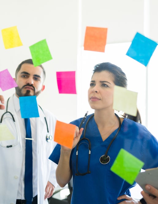 A group of people looking at sticky notes on a glass wall