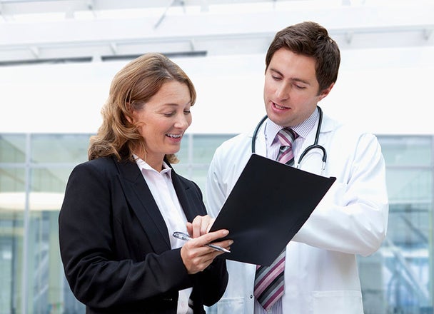 An administrator and a doctor review a document in the medical office.
